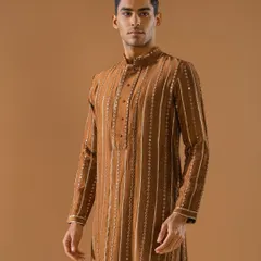 This handsome brown kurta is detailed with vertical stripes of delicate embroidery and mirror work. It is a perfect example of timeless luxury meeting seasonal vibrance.