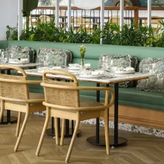 I used a combination of seating styles, including this plush green banquette and natural rattan chairs. The custom-printed cushions add a touch of botanical art, reinforcing the overall nature-inspired theme of the restaurant interior.