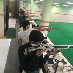 A line of shooters practicing with high-precision air rifles. Each one is focused on their own lane, working on the techniques needed for competitive target shooting.