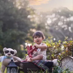 With a toy airplane in hand and a look of wonder, this tiny traveler is ready for takeoff. The outdoor setting adds a sense of real adventure.