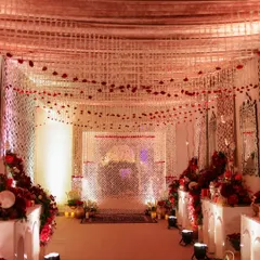 The entrance to this royal-themed event featured a ceiling of floral strings and red roses, leading guests down a path flanked by elegant table settings.
