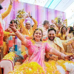The couple is showered with flower petals by their loved ones during a joyous and energetic Haldi ceremony.