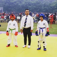 Two young competitors facing off before their sparring match begins, with the referee ready. This moment of focus and respect is a core tenet of Taekwondo.