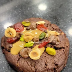 A close-up of the rich toppings on my Dark Chocolate Overload Cookie. You can see the combination of crunchy nuts, chewy dried fruit, and creamy chocolate.