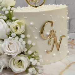 A closer look at the details. The combination of fresh baby's breath, white roses, and scattered pearls gives this engagement cake a truly romantic and dreamy feel.