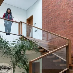 An exposed brick wall adds texture and warmth to this double-height space. The glass-paneled walkway on the upper level maintains an open and airy feel, allowing light to travel freely while connecting different parts of the home.