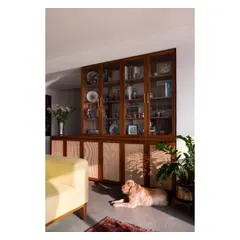 A custom teak and rattan crockery unit, perfectly sunlit and watched over by the home's most relaxed resident.