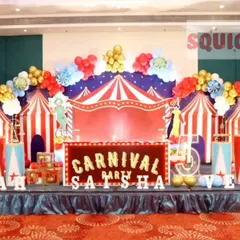 A spectacular carnival-themed birthday stage. This grand setup includes a circus tent backdrop, a Ferris wheel, popcorn props, and marquee letters, creating a funfair atmosphere.