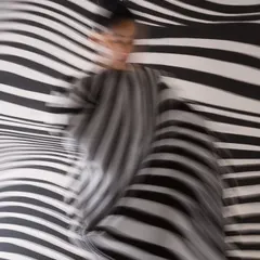 Using a slow shutter speed to capture the movement of the pleated dress against the static background. This technique turns the graphic campaign into a dynamic, abstract image.