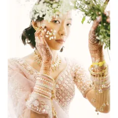 An artistic bridal portrait with a fine art feel. The bride's pose, combined with the delicate flowers, creates a beautiful and ethereal image that feels both candid and composed.
