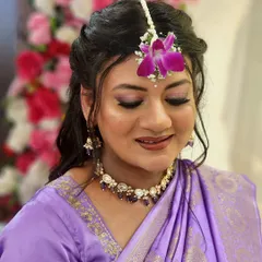 A glowing mommy-to-be in a lovely lilac saree for her baby shower, with her makeup featuring soft purple tones on the eyes.