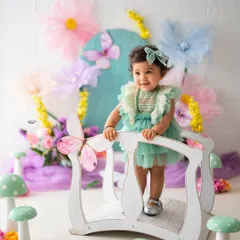 This little cutie is exploring her own secret garden, complete with a tiny white bridge and colorful toadstools. The pastel palette is perfect for a first birthday photoshoot.
