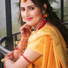 This bride is ready for her Haldi ceremony in a simple yellow saree, accessorized with beautiful floral jewelry. The makeup is kept fresh and bright with a pink lip.