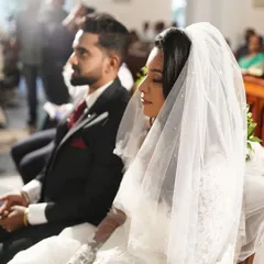 A serene shot of the couple during their wedding vows. The bride's makeup is subtle and elegant, with a focus on flawless skin and defined eyes, perfect for the solemnity of the occasion.