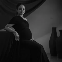 A graceful seated portrait in black and white. Removing the color allows the focus to be on the mother's serene expression and the classic lines of her pose.