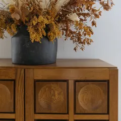 A detail of the Brutalist-inspired oak sideboard in the Corner House dining room. The deep, geometric carving on the doors adds a strong textural element to the space.