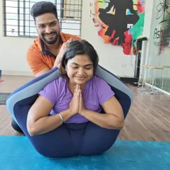 A moment of achievement in Yoganidrasana (Yogic Sleep Pose). My gentle assistance helps the student comfortably settle into this complex forward bend, showcasing our supportive teaching style.