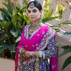 The complete bridal look for a beautiful Sikh bride. Her hair is styled in a traditional floral bun that provides a perfect base for her ornate dupatta and heavy jewellery, ensuring she looks regal throughout her wedding day.