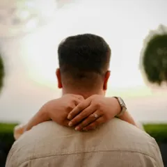 A beautiful shot from behind, with her arms wrapped around him. The focus on her hands and the engagement ring tells a story of love, trust, and a shared future.