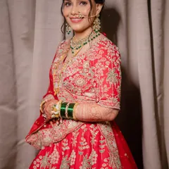 A full-length shot of the bride in her stunning red embroidered lehenga. The elegant updo and confident smile complete this perfect look for a wedding reception.