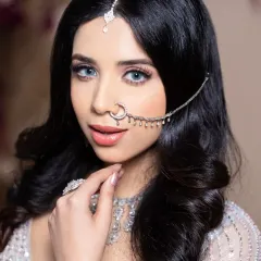 A modern reception look created by a student, featuring bright blue eyes and a sparkling silver lehenga.