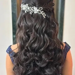 Another beautiful half-up hairstyle with voluminous curls and a floral crystal accessory, demonstrating a timeless and romantic look.