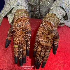 A close-up of the rich henna stain, showing the name 'Tauhid' clearly visible within the intricate floral design.