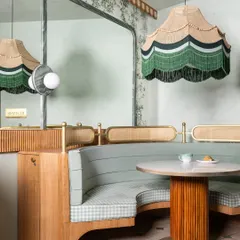 A detail from 11 Grams Cafe, this shot highlights our love for bespoke elements. The custom scalloped pendant lamp with green fringe hangs above a curved booth upholstered in gingham, creating a cozy nook that balances nostalgia with modern design.