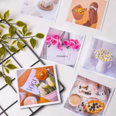 A collection of aesthetic square photo prints arranged on a grid with some greenery. This shot is great for showcasing a product that helps customers create a vision board or decorate their room.