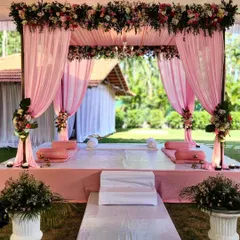 This elegant pink mandap was designed for an outdoor engagement. The soft drapes are complemented by a thick border of multi-colored premium flowers, with a chandelier adding a touch of glamour.