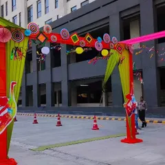 This daytime view shows the detail of a colorful entrance gate. I used a mix of paper crafts, pinwheels, and fabric drapes in green, red, and pink to create a vibrant welcome for guests.