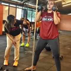 Locked in and zoned out. A coach provides guidance and correction during a challenging dumbbell exercise, showcasing our hands-on approach.