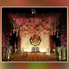 A magnificent floral mandap designed for a traditional wedding ceremony. The backdrop is a wall of white flowers, while the ceiling is adorned with hanging floral tassels and temple bells, creating a sacred and beautiful space.