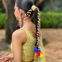 A full view of the Haldi look, showing how the long, accessorized braid complements the bride's vibrant yellow lehenga. This hairstyle is a statement piece in itself.