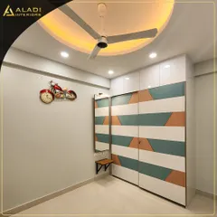 A playful and modern sliding wardrobe with a geometric pattern in white, teal, and terracotta colors. A small attached mirror and shelf add to its functionality.