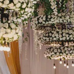 A detailed shot of the custom-made floral chandeliers, with rings of white carnations and exposed Edison bulbs for a touch of modern elegance.