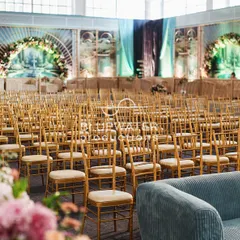 The guest seating area for the 'Blue Palace' reception, with rows of gold chairs facing a stage flanked by artistic, printed panels.