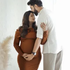 A tender moment captured between a couple during their maternity photoshoot. The partner's gentle kiss on the forehead adds a layer of warmth and emotion to the portrait.