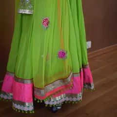 The beauty of an Anarkali is in its details. This shot highlights the lower hem, featuring a broad pink border, silver gota patti lining, and small green tassels that add a playful, finishing touch to the outfit.