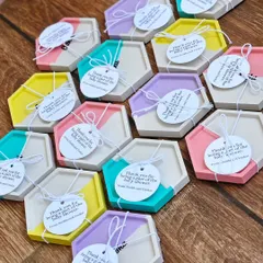 A full view of the custom name coasters made for a baby shower return gift. Each one is tied with a personalized 'Thank You' tag from the parents-to-be.