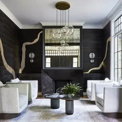 This room is a masterclass in texture. The 'Adorn' wallcovering, with its Kintsugi-inspired metallic lines, provides a dramatic backdrop for the boucle armchairs and marble fireplace, creating a space of sophisticated luxury.