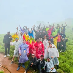A large, happy group in colorful raincoats celebrating reaching a viewpoint on the Bandaje Falls trek. The energy and camaraderie are what make these trips special.