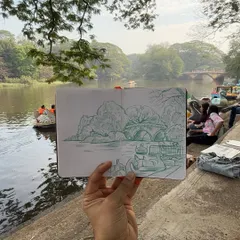 There is a special connection formed when you draw a place while you are in it. I held up my finished sketchbook to show my pen drawing against the real boating lake at Sanjay Gandhi National Park. My goal is to capture the essence of the scene, not just a perfect copy.