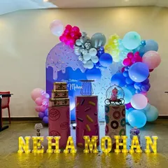 A delicious-looking donut and sweets theme for Neha and Mohan. This setup features donut-printed pedestals and a colorful balloon arch against a sprinkle-themed backdrop.