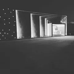 An artistic, black and white perspective of the HLP Galleria project. This view emphasizes the pure form and rhythm created by the linear lights and the dramatic shadows they cast, showcasing the sculptural quality of the lighting design.