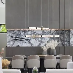 The Luna series by Gabriel Scott demonstrates how linear lighting can become the centerpiece of a grand dining space. Its modular design, featuring blown glass and metallic finishes, is suspended against a dramatic marble wall, creating a statement of sophisticated, contemporary luxury.