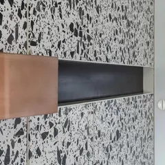 A close-up of a copper cuboid wedged into a terrazzo panel, a detail that exemplifies our use of angular forms and contrasting materials.