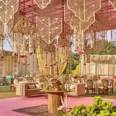 A beautiful lounge area set under a canopy of floral chandeliers and golden mesh, with a blush pink carpet unifying the space.