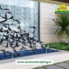 This custom water feature includes a dynamic metal sculpture of a flock of birds taking flight, creating a striking centerpiece for a modern villa landscape.