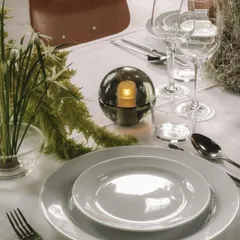 The Bocci 14p in Smoked Grey, used as a centerpiece on a beautifully set dining table. It provides an intimate, candle-like light without the worry of an open flame.